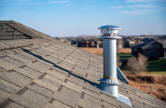 Photo of a rooftop vent pipe with a protective cap, illustrating residential roofing details.