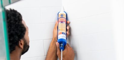 Man applying caulk in shower