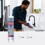 Image of a man applying silicone caulk for tub and tile in a modern kitchen.