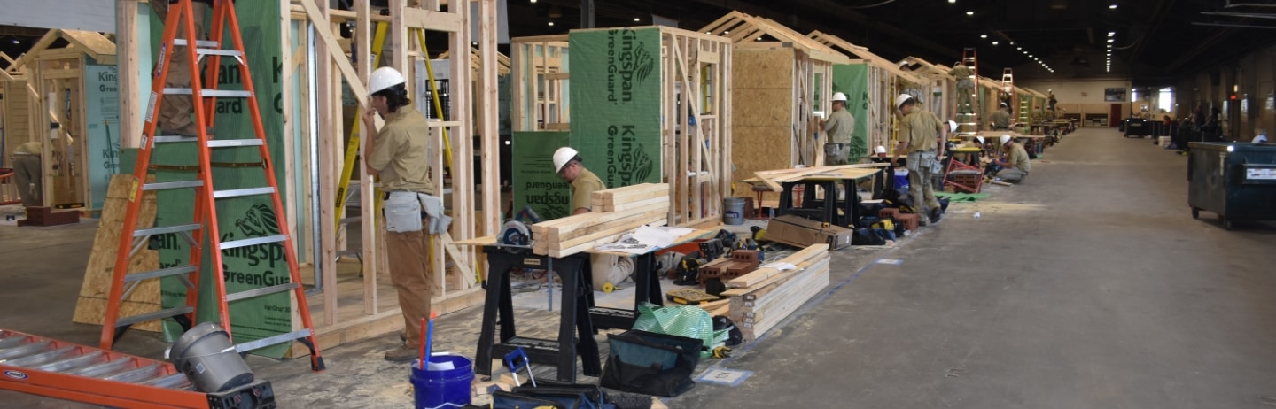 Photo of a construction site with workers, tools, and wooden frame structures.