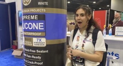 Photo of a person in front of a display for supreme silicone sealant at a trade show booth.