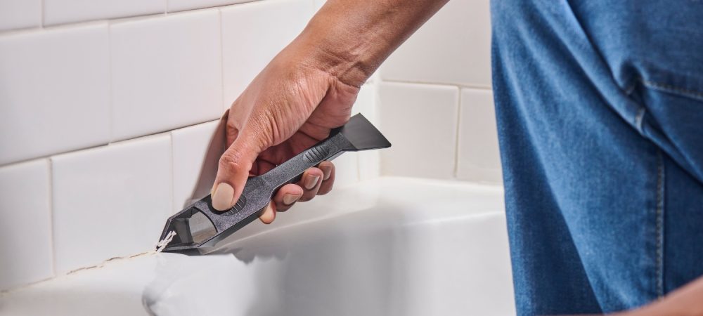 A photo of a homeowner removing old sealant with GE’s Sealant Remover Tool.