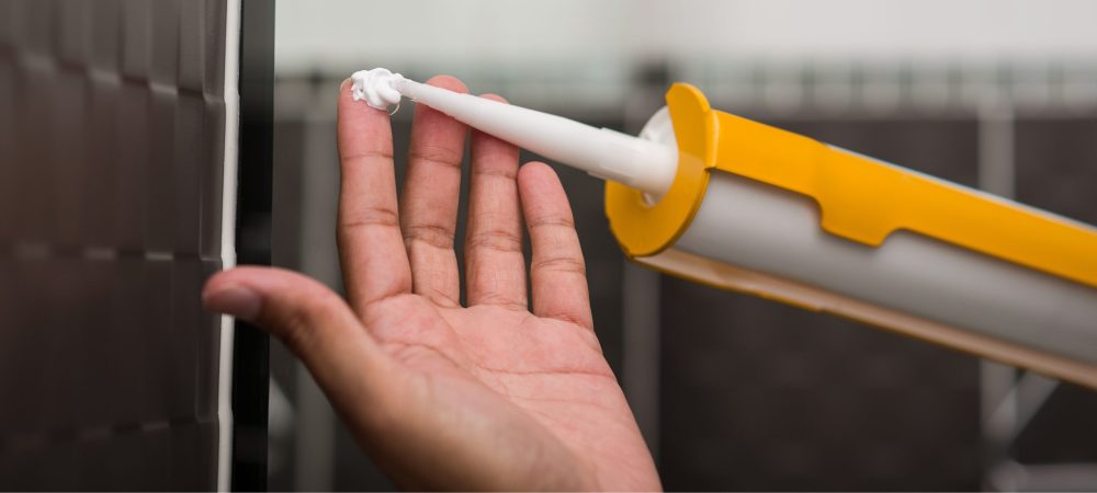 A photo of silicone sealant on a person’s hand.