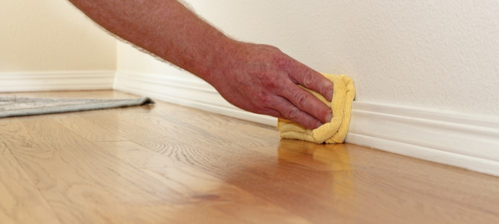 This image shows someone cleaning a surface before learning how to caulk trim.