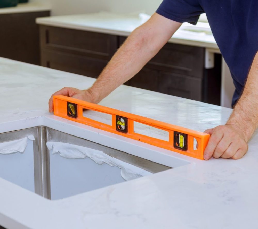 Countertop sink opening being checked for alignment during an undermount sink installation.