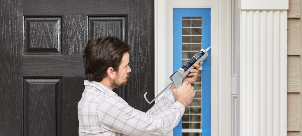 A handyman sealing a window