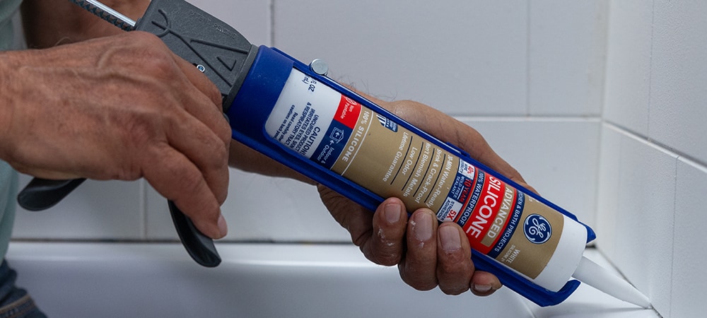 A plumber applying silicone sealant