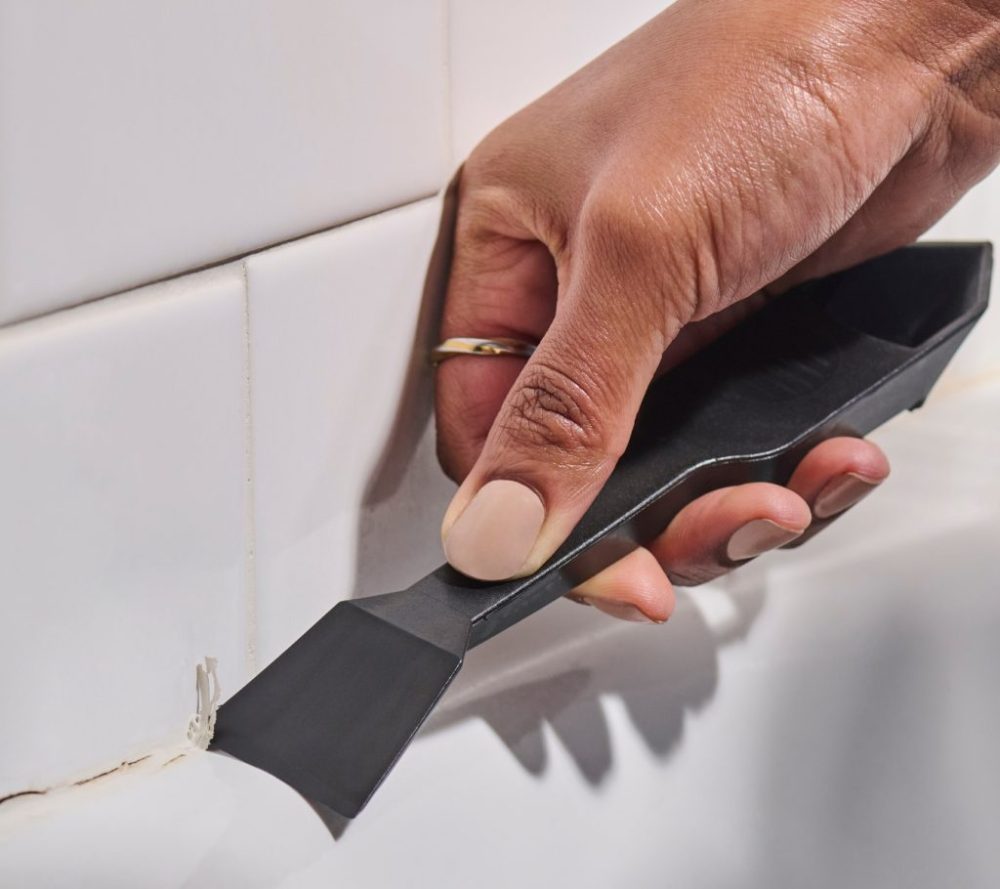 A homeowner removes old sealant with GE’s Sealant Remover Tool.
