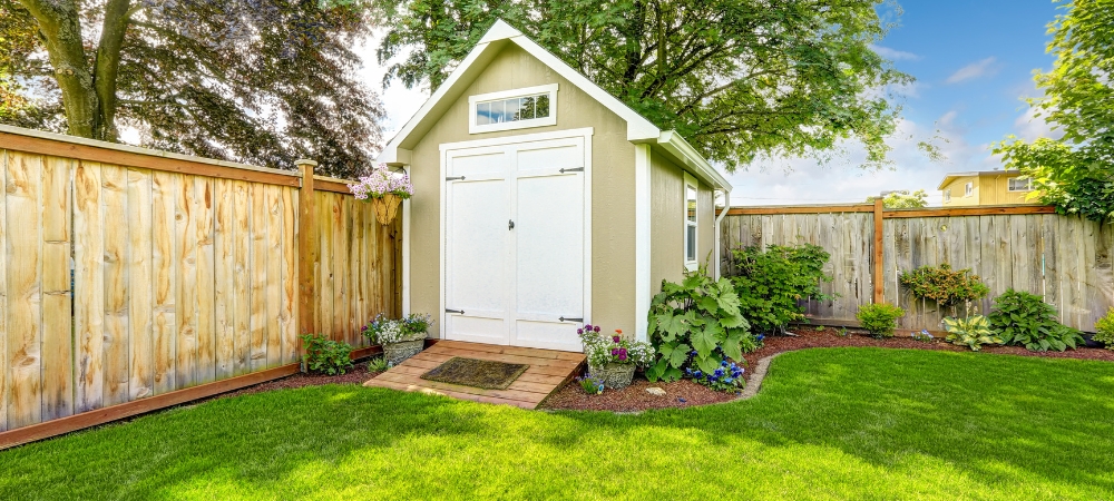 Applying sealant around a garden shed door to prevent water seepage.