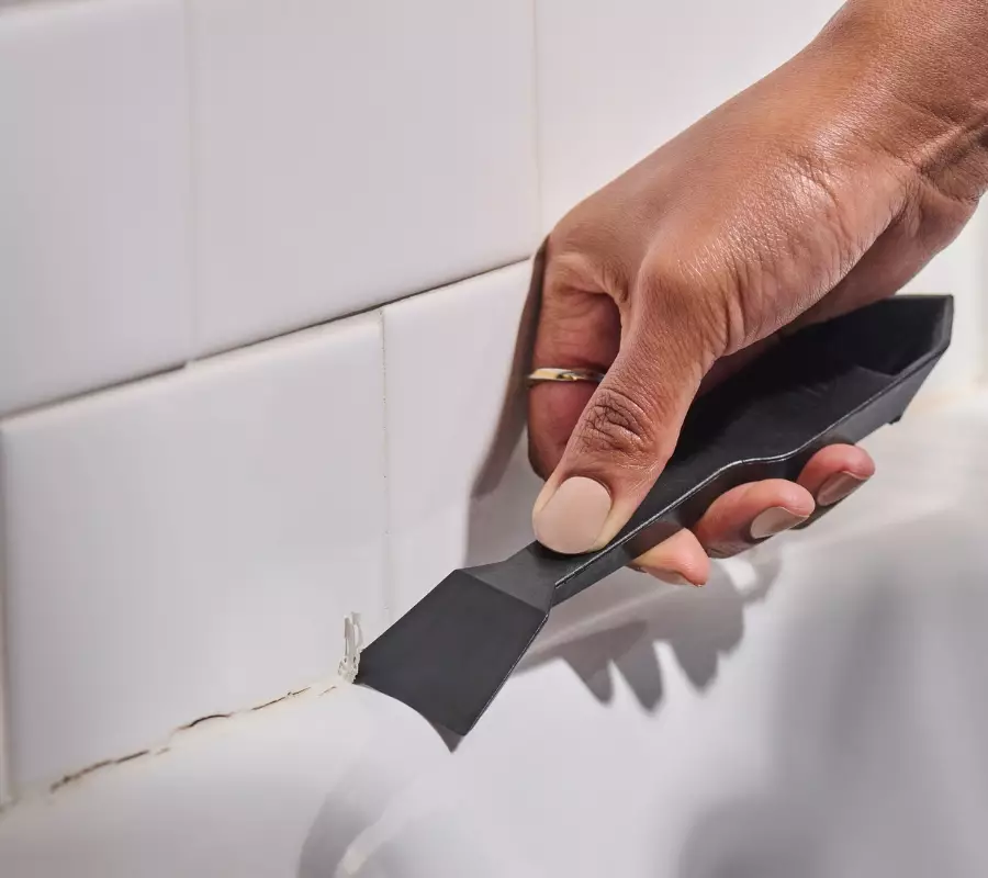 A homeowner uses GE’s new Sealant Remover Tool to remove old sealant.