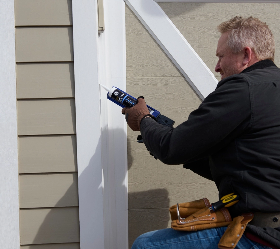 Someone using GE Pro Seal Max Window & Door to seal exterior trim before rain.