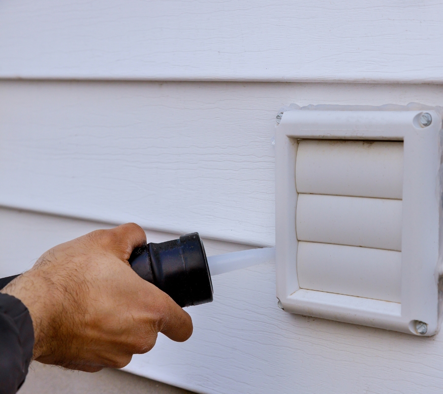 Sealing a metal dryer vent trim with high-temperature silicone sealant for outdoor heat exposure.
