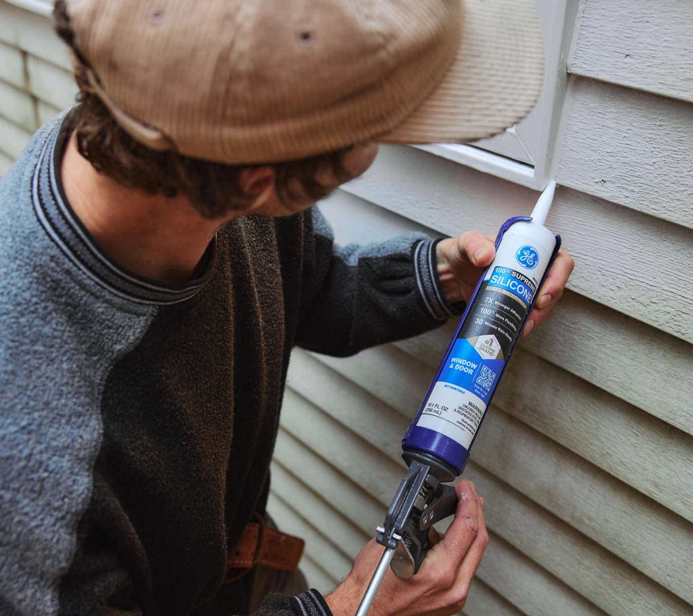 Applying weatherproofing sealant to an exterior window frame, targeting a high-risk zone for moisture and air leaks.