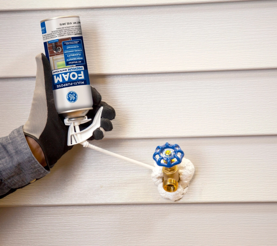 GE Multipurpose Foam Sealant fills a gap around an exterior pipe in a foundation wall.
