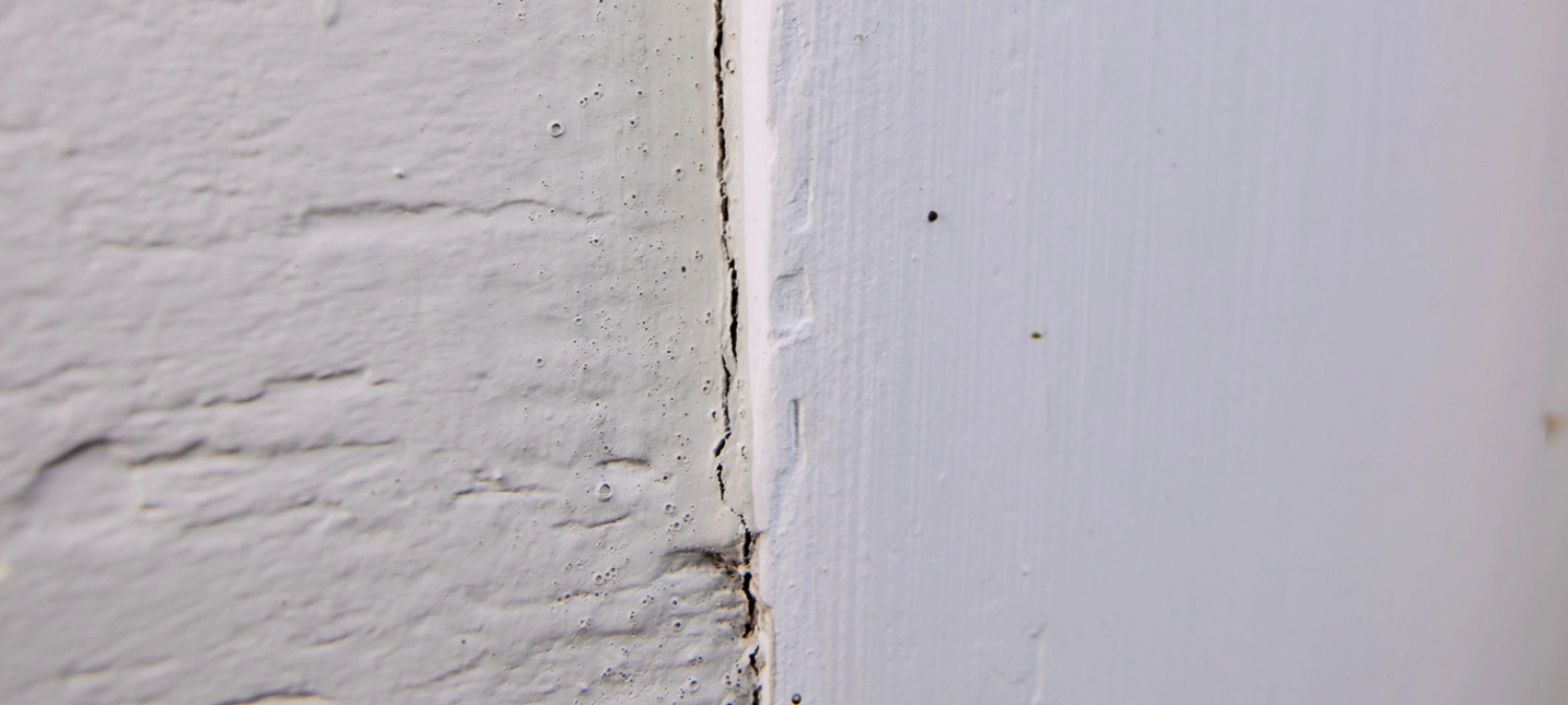 Cracked and lifting sealant on siding exposed to sun and rain.