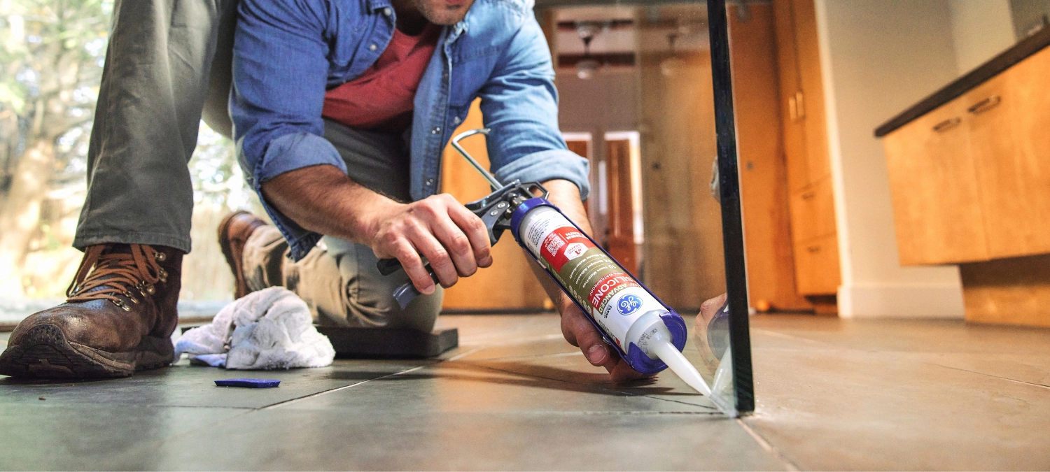 A person applying clean silicone sealant in the bathroom.