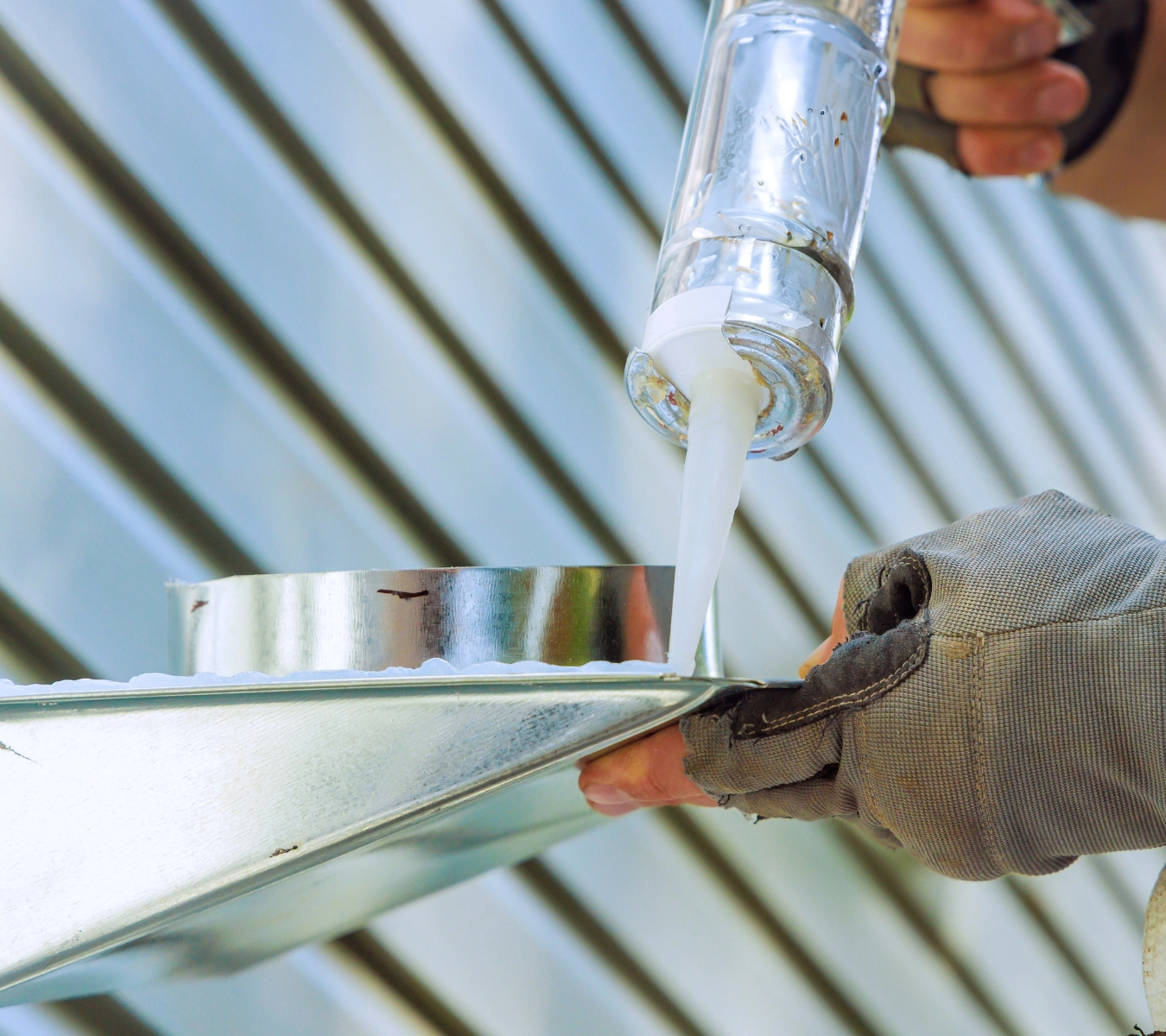 Smoothing a bead of roof sealant along flashing.