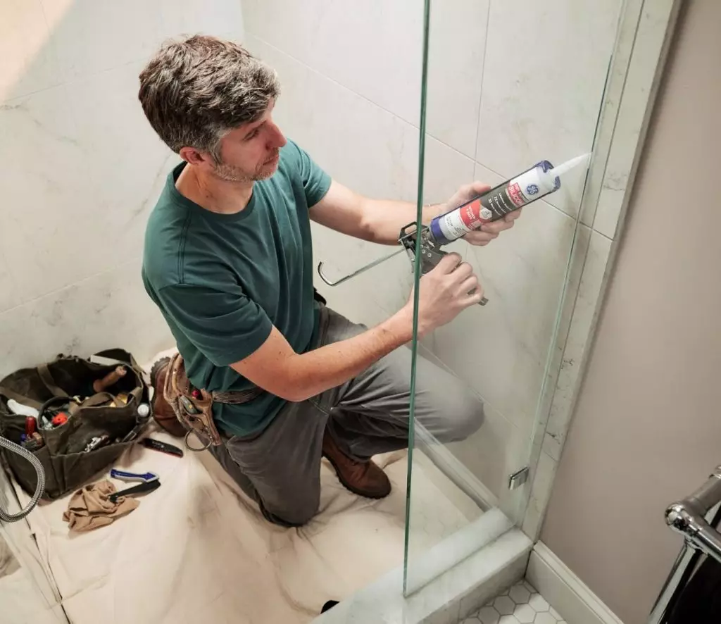 A photo of a homeowner applying GE Supreme Silicone Kitchen & Bath Sealant.