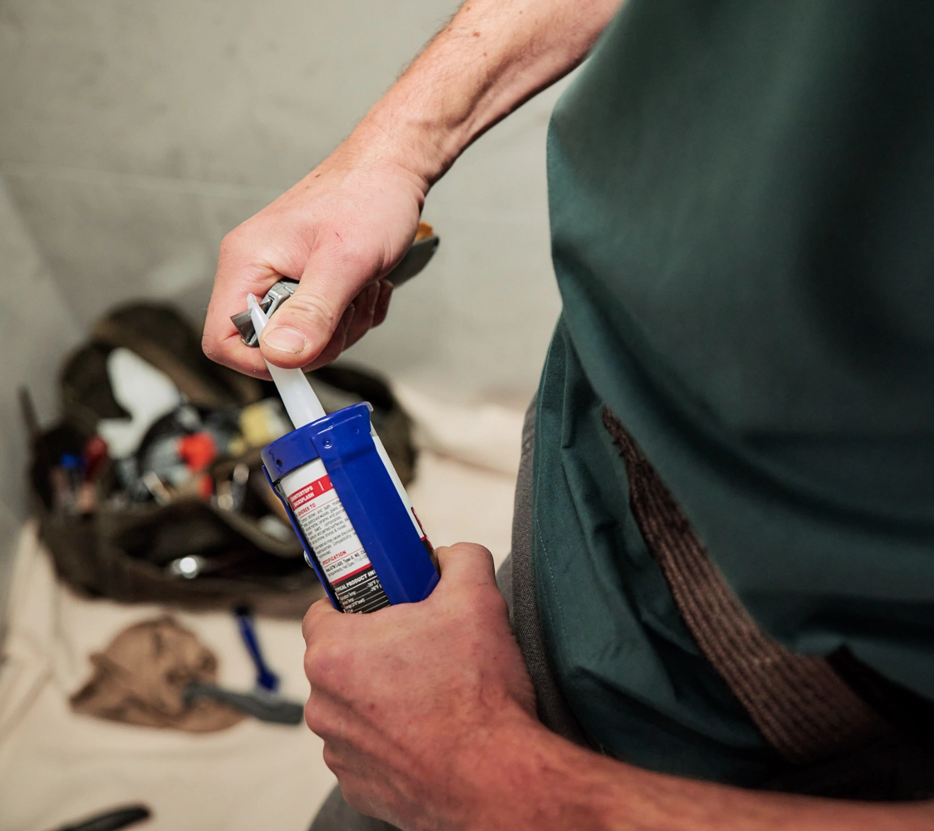 Someone cutting a sealant nozzle at a 45-degree angle for bathroom caulking.