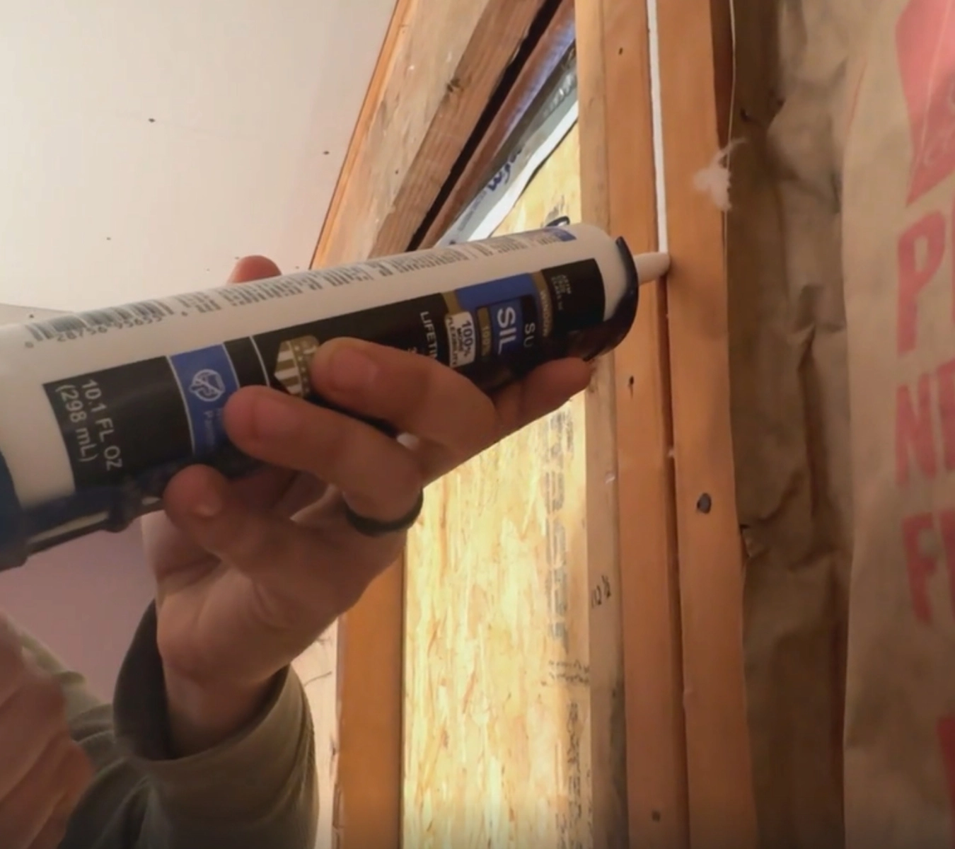 Person applying silicone sealant before drywall installation.