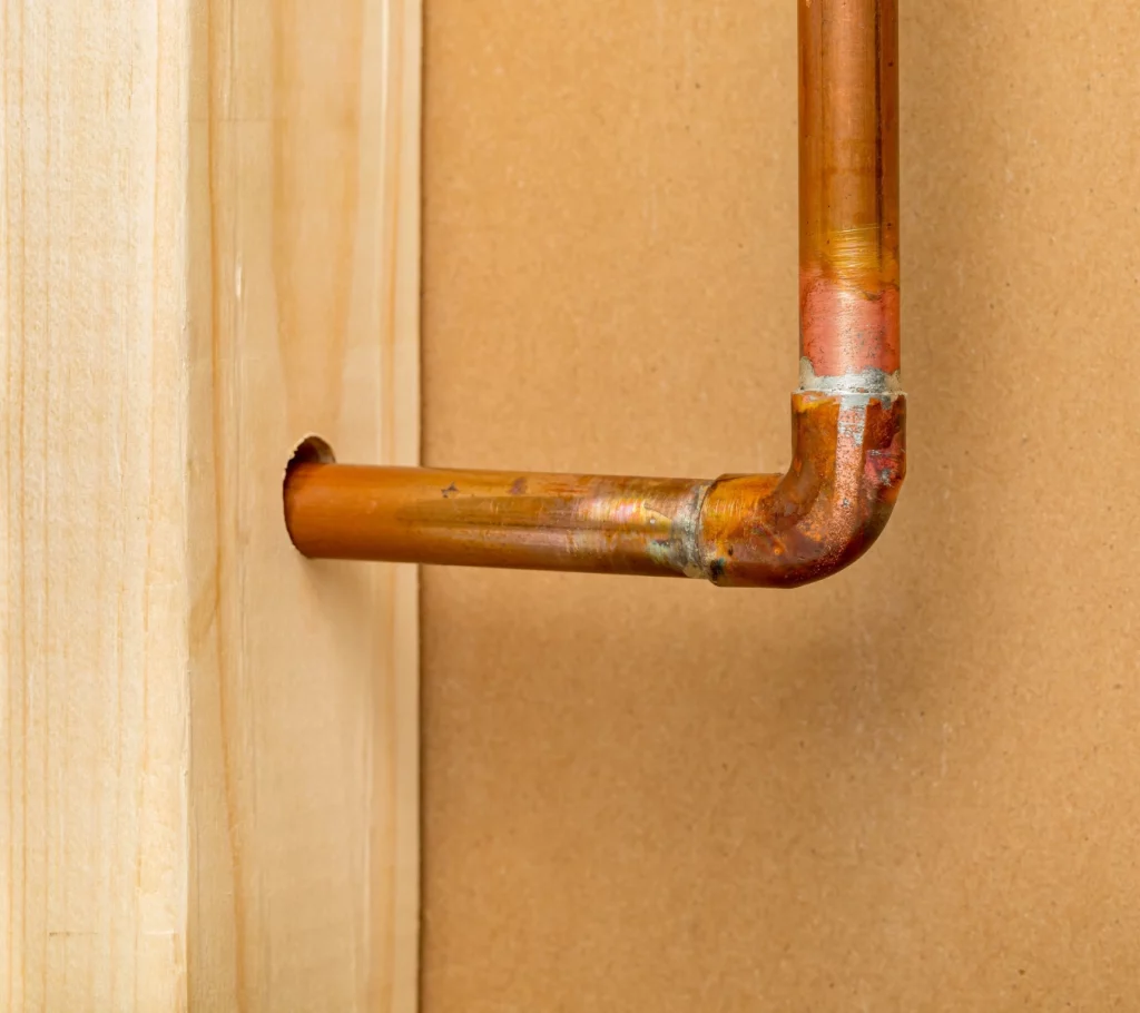 A photo of a gap between a copper water pipe and the wall