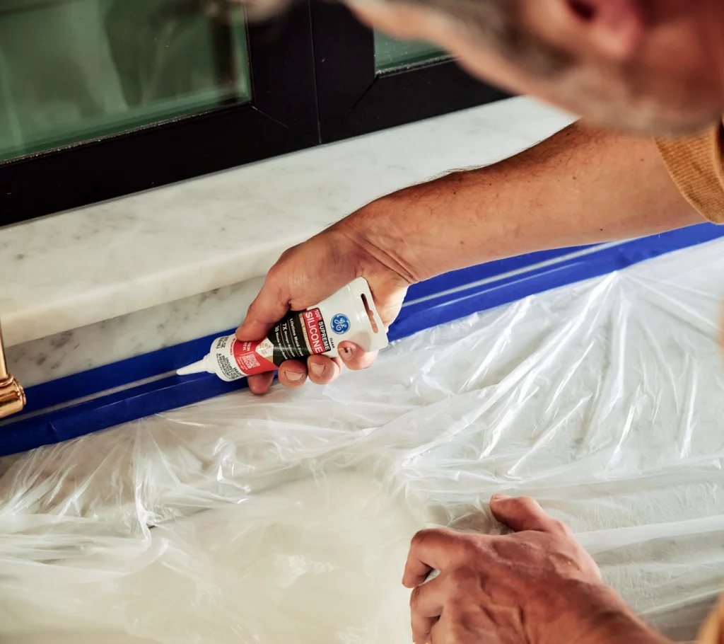 Image of someone applying silicone sealant in the kitchen.