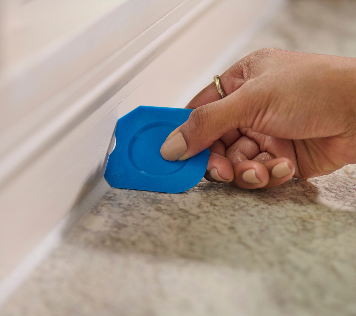 A person using the GE Sealant Smoothing Tool to create a watertight silicone seal along a countertop.
