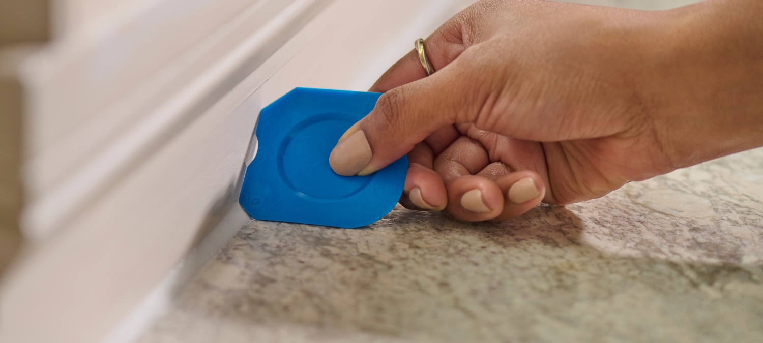 Contractor using a GE Sealant Smoothing Tool to form a clean silicone sealant line along a kitchen backsplash.