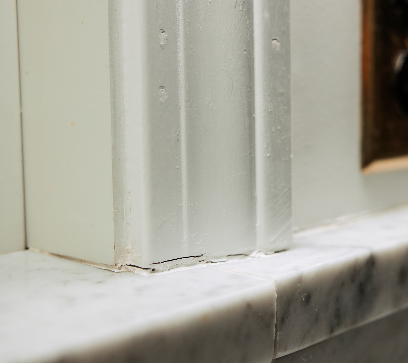 Checking cracked window caulk during a winter home audit to find air and water leaks.