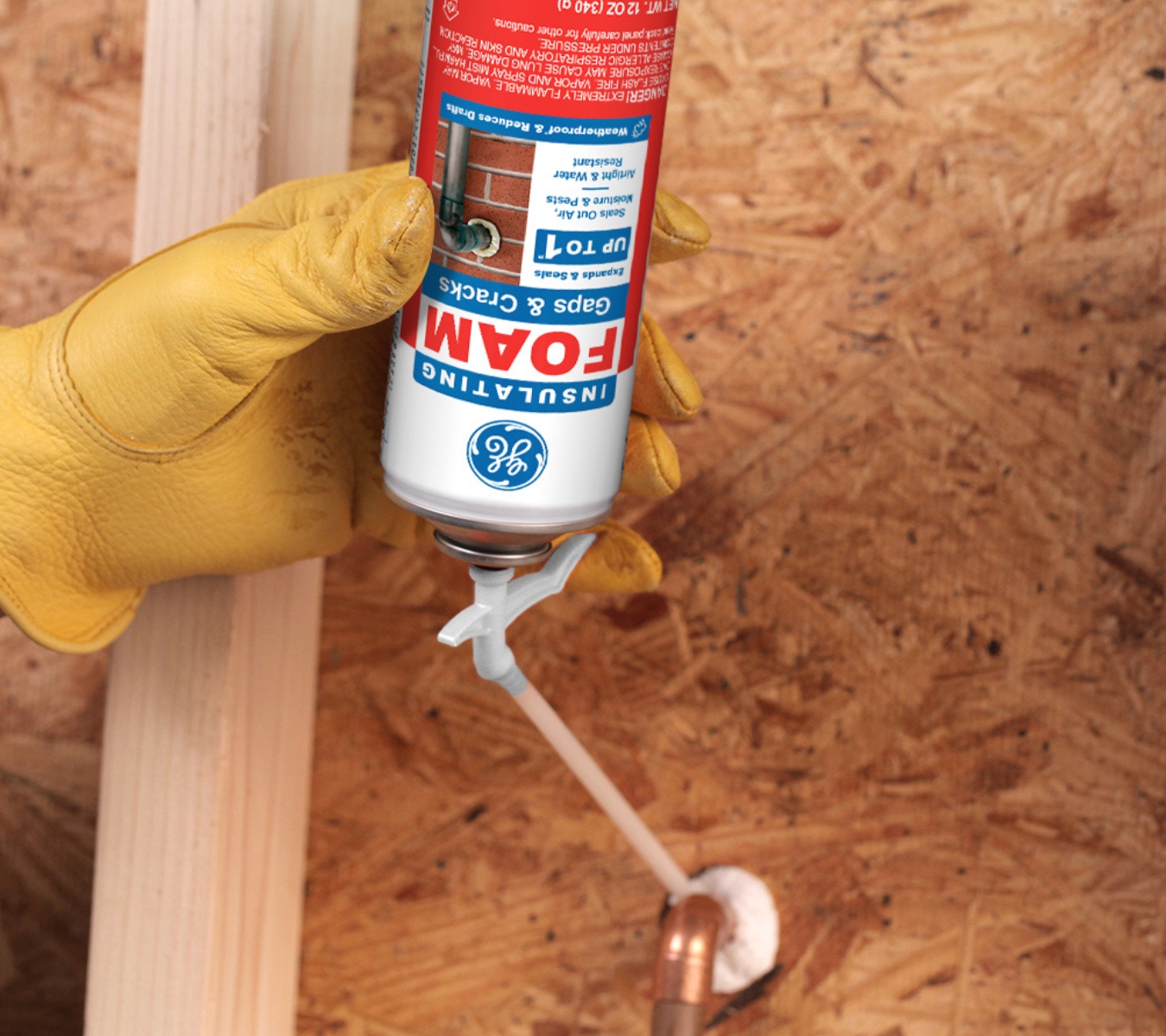 GE Gaps & Cracks Insulating Foam is being applied around a pipe penetration to block air and moisture leaks in a garage.