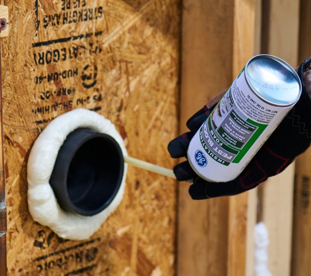 Closing gaps around attic utility penetrations with GE Pest Block Insulating Foam to stop hidden air leaks.