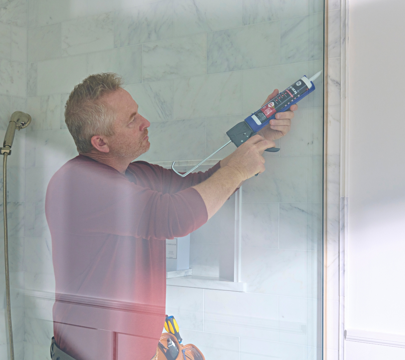 Homeowner applying a bead of GE Pro Seal Max Kitchen & Bath Sealant along a shower edge.