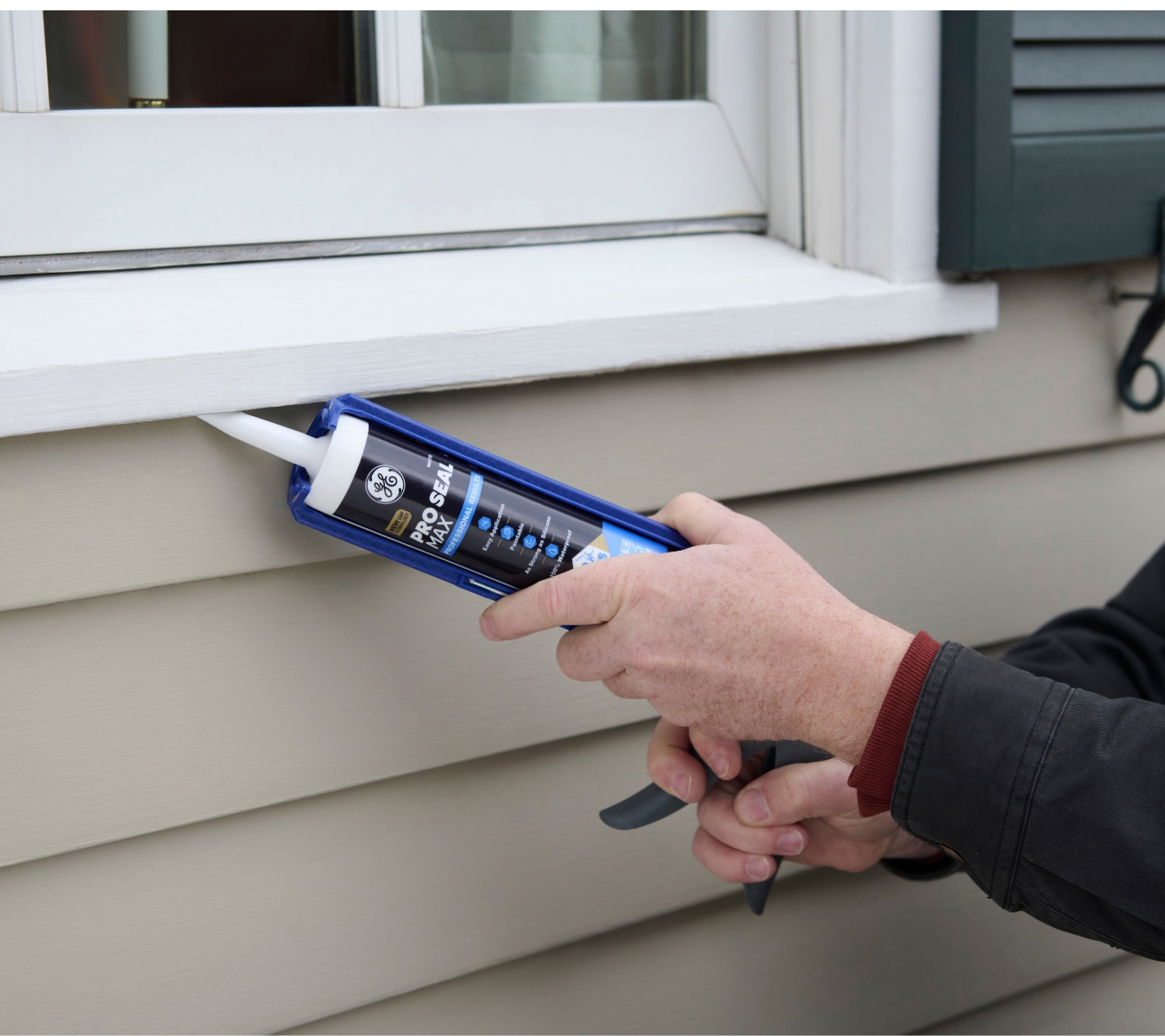 Contractor applying GE Pro Seal Max Window & Door to an exterior window frame to prevent leaks.