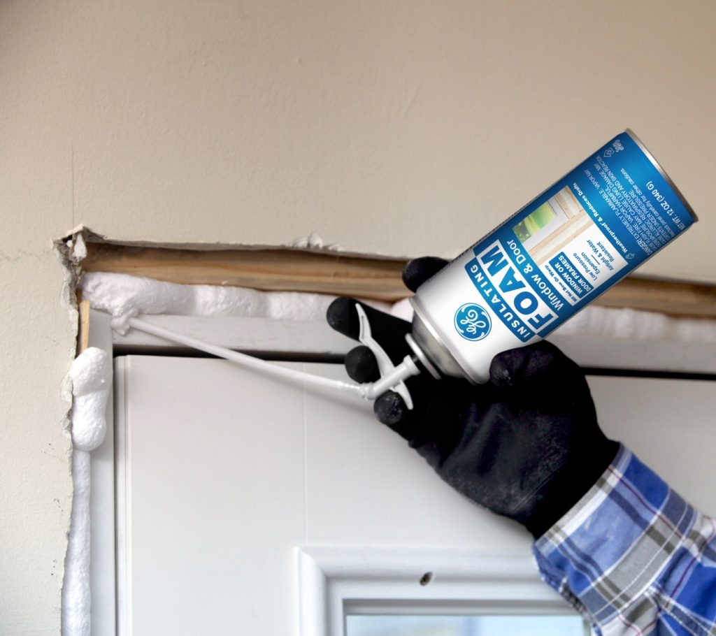 Homeowner applying GE Window & Door Insulating Foam behind door casing to seal large gaps and prevent drafts.