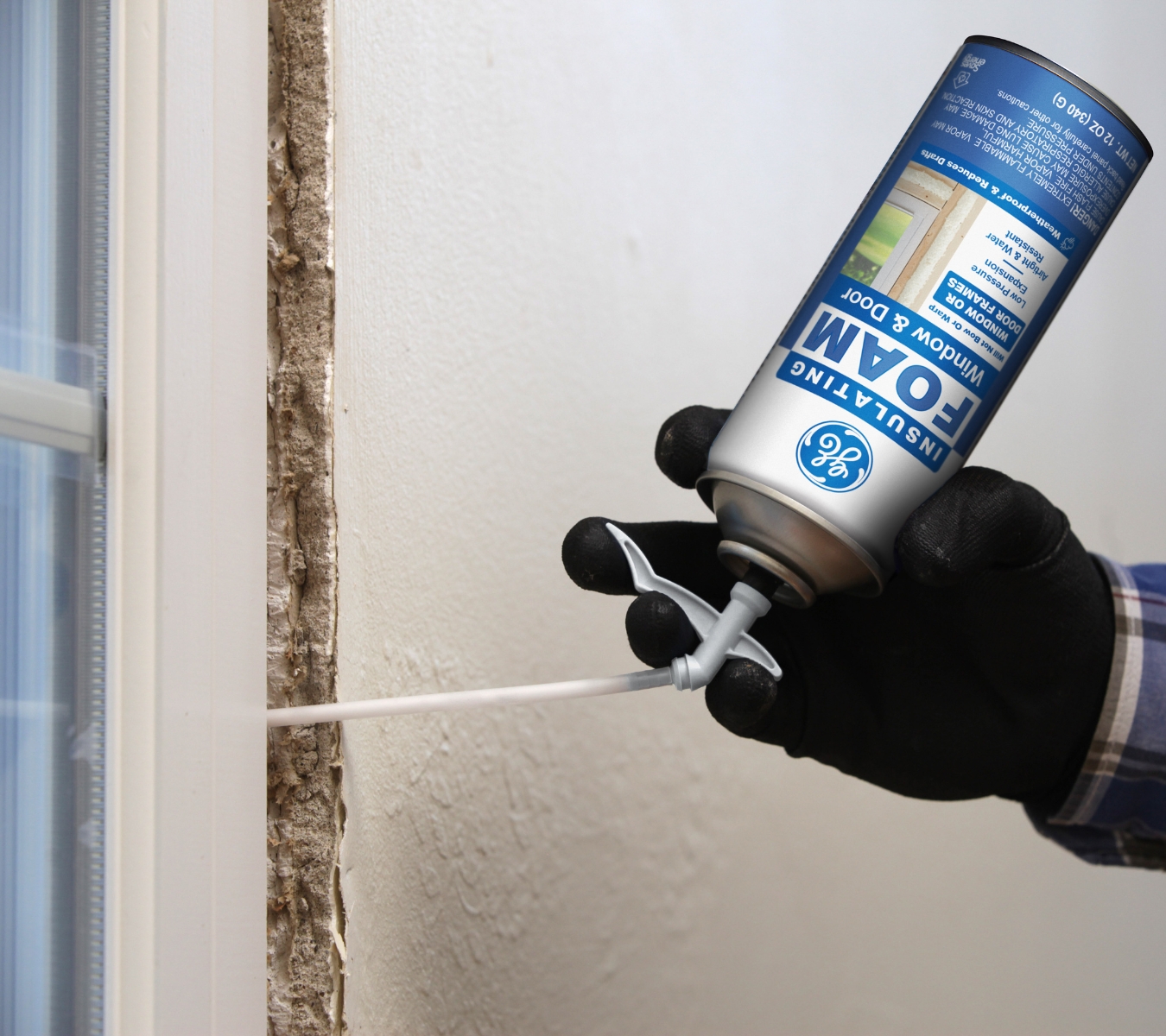 Applying GE Window & Door Insulating Foam with a controlled bead around a window frame.