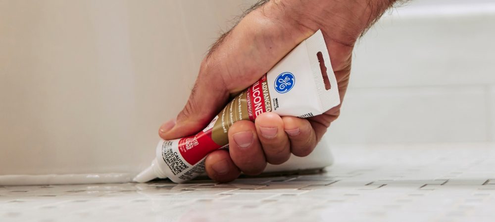 A photo of caulk around the base of a toilet.