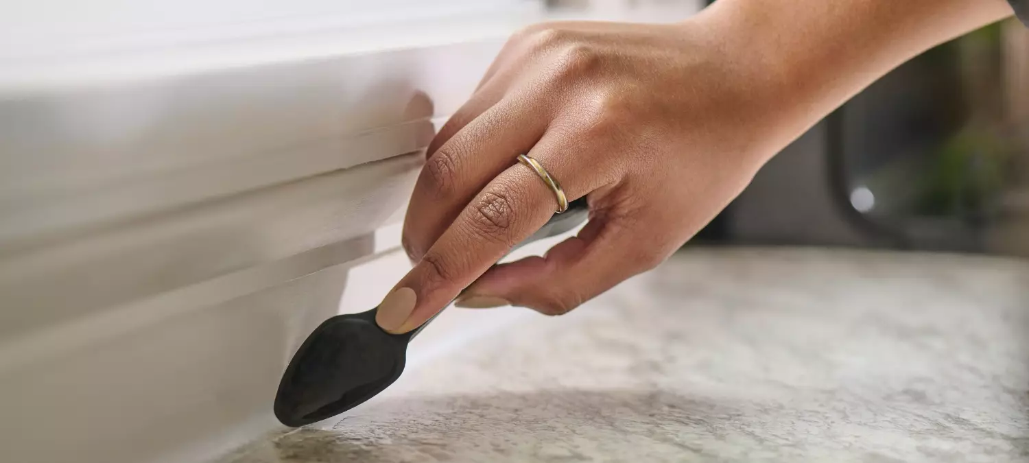 A close-up shows a hand smoothing sealant along a trim edge using the GE Cartridge Opener and Smoothing Tool.