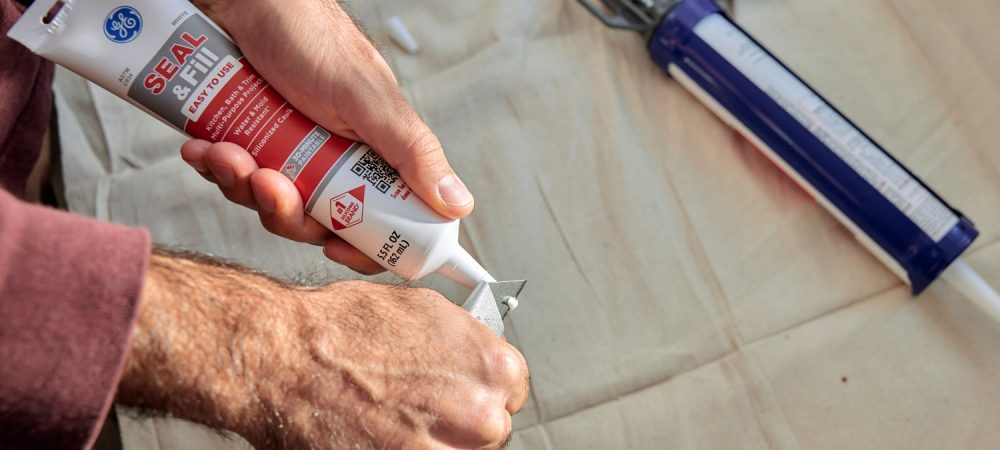 A photo of a nozzle being cut on a tube of caulk.