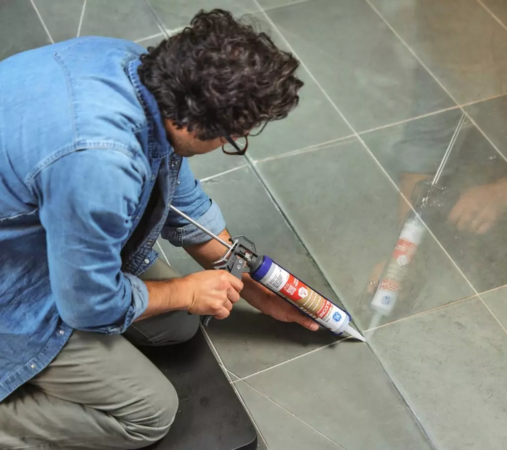 A photo of a homeowner using GE Advanced Silicone Kitchen & Bath applied in a bathroom.