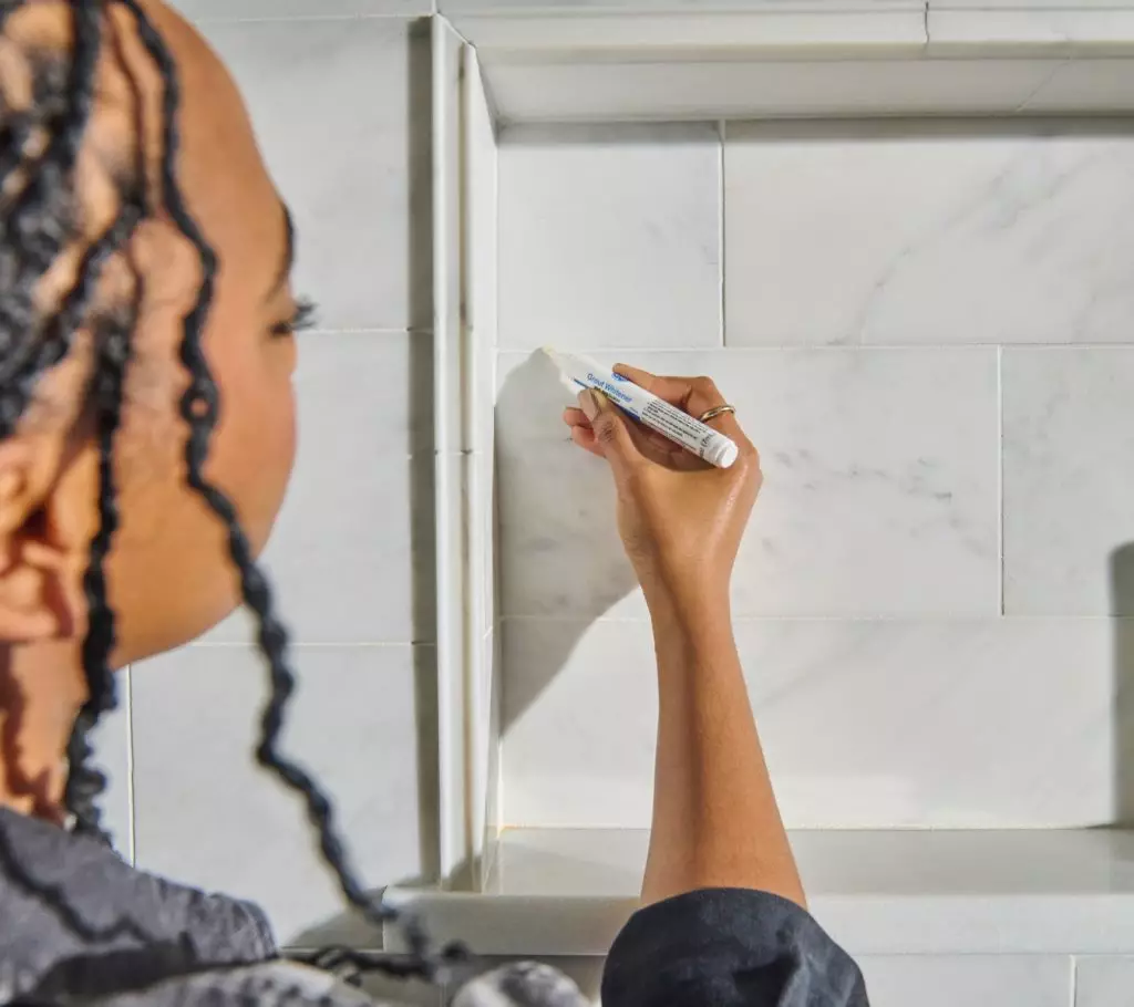 A photo of a homeowner applying GE’s Grout Whitening Pen.
