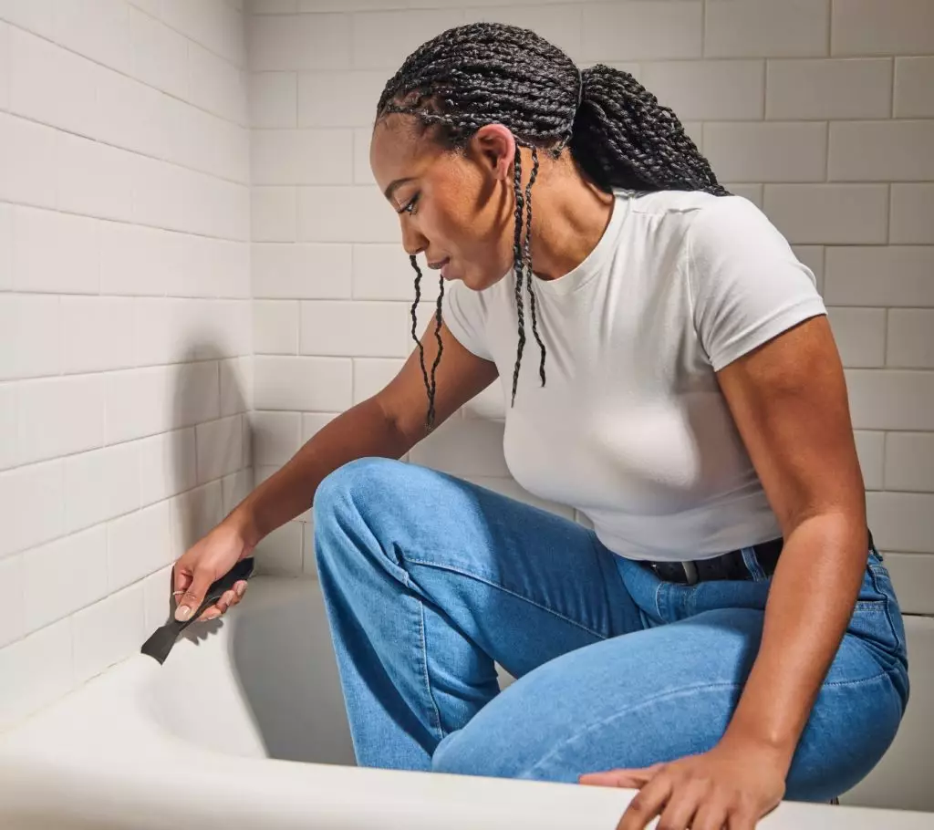 A photo of a homeowner removing sealant with GE’s Sealant Remover Tool.