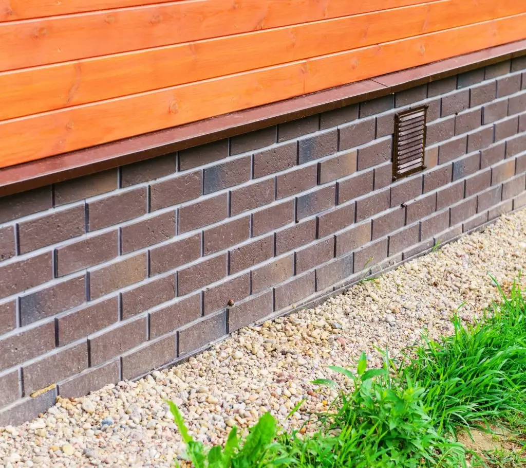 Siding over brick foundation with horizontal transition seam.