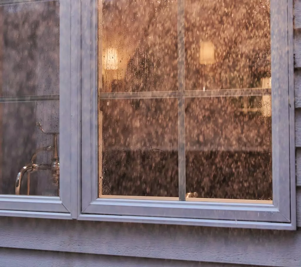 An exterior window of a home, covered in rain.