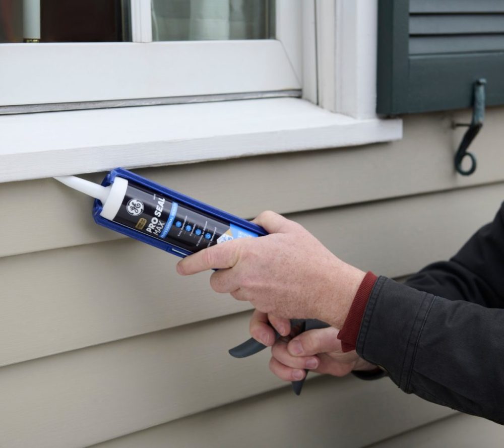 A contractor applying GE Pro Seal Max Window & Door at an exterior window perimeter where the finished bead will be painted.